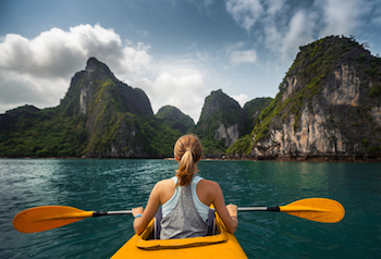 Woman kayaks by scenic mountains 